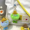 Macro view of colorful fuzzy monster keychains hanging on a stylish white canvas tote bag - Green