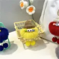 Macro detail of a yellow plush pom-pom keychain with a knit hat and big eyes - Yellow