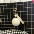 Detail of white faux fur pompom keychain with elegant pearl charm and tweed fabric strap - White