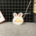 Detail view of a cute white fluffy rabbit plush keychain with a tiny yellow hairclip - Single OPP Bag Packaging / Yellow