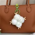 Detailed view of a creative fermented bean curd plush keychain charm on a brown leather bag - Green