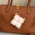 Close-up of a cute plush food-themed keychain hanging on a brown leather handbag - Orange
