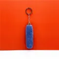 Close-up detail of a fluffy blue faux fur plush keychain pendant with a gold metal ring. - Blue