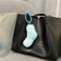 Detail showing a cute light blue plush sock-shaped keychain on a black leather bag - Single OPP Bag Packaging / Sky Blue