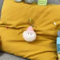 Close-up detail of cute plush pom-pom keychain with pink hat and big eyes for bag charm - 1 Piece / Pink