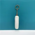 Close-up detail of a soft white plush furry tassel keychain with a elegant gold-finish metal ring - White