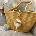 Colorful plush lollipop keychains with lace bows hanging on a woven straw tote bag - 1 Piece / Pink