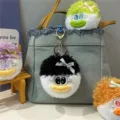 Close-up of cute plush doll keychains with messy hair on a denim bag - Black