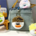 Fluffy plush monster doll keychains displayed as cute bag charms on a denim handbag - Khaki