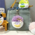 Detail eines süßen, lila flauschigen Plüschpuppen-Schlüsselanhängers an Denim-Tasche - Lila