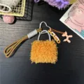 Close-up of a stylish orange fuzzy bag charm featuring a pink balloon dog accessory - Orange