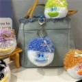 Nahaufnahme von niedlichem blauen flauschigen Plüschmonster-Schlüsselanhänger an Jeanstasche - Himmelblau