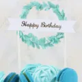 Close-up detail of green leaf wreath birthday cake topper with Happy Birthday banner - Light Blue Leaf Happy Birthday