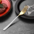 Elegant gold stainless steel dining fork with a minimalist white handle for table decor - Dinner Fork / White