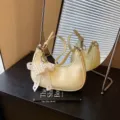 Elegante hellgelbe Unterarmtasche aus Knautschleder mit Perlenspitzen-Schleifenanhänger. - Mit Anhänger / Gelb
