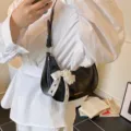 Elegante schwarze Unterachseltasche aus Ölhaut mit weißer Schleife und Perlenanhänger - Mit Anhänger / Schwarz