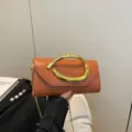 Elegante orangefarbene Lederkupplung mit einzigartigem goldener Griff und einer feinen Kette - Braun