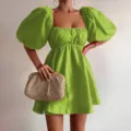 Green square neck puff sleeve mini dress detail view with woven straw clutch bag matching. - S / Yellow