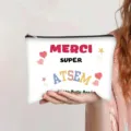 Detail view of a white canvas makeup bag held by hand featuring Merci Super Atsem print - French Style (Merci ATSEM)