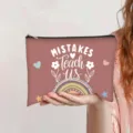 Canvas makeup pouch featuring 'Mistakes Teach Us' quote with rainbow and floral design. - Dusty Pink (Mistakes teach us)