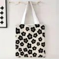 Detalle de bolsa de lona con estampado floral negro colgada en un gancho de pared - Gran Floral Negro Blanco / 34x39cm