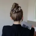 Detail of a coffee brown satin scrunchie styled on a classic bun hair style. - L / Brown Gray