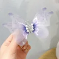 Beautiful lavender purple tulle butterfly hair clip with white pearl accents held by hand - Purple