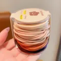 Vista detallada de elásticos para el pelo de niños en un contenedor transparente - 48 Piezas por Juego / Serie Naranja
