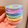 Primer plano de gomas elásticas de colores para el pelo de niñas en caja redonda clara - 48 Piezas por Juego / Color macarrón