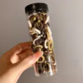 Transparent cylindrical bottle filled with assorted neutral brown and beige hair ties. - 100 Pieces/Jar / Neutral Series (5#)