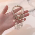 Detailed close-up showing white lily of the valley tassels and pearl bow on gold hair clip - Bowknot Lily of the Valley