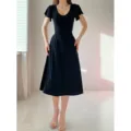 Détail de la super élégante robe midi noire avec des manches évasées et taille ajustée. - Robes midi noires