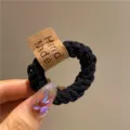 Dettaglio di un elastico per capelli nero intrecciato ad alta elasticità con etichetta. - Nero