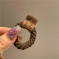 Vue détaillée d'un chouchou élastique marron épais avec une étiquette en cuir faite main - Café Foncé