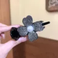 Macro detail of a sparkling rhinestone four-leaf clover hair clip with central pearl - Clover Black Bun Clip / Black