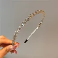 Nahaufnahme eines eleganten Haarreifs mit Kristallen und goldenen Perlen für Damen - Grau