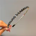 Detailansicht eines eleganten schmalen Haarreifs mit schwarzen Kristallen und Goldperlen - Marineblau