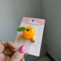 Cute 3D orange fruit hair clip with green leaf detail presented on pink backing card - 2 Pieces/Pack / Orange