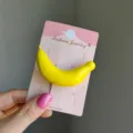 Cute yellow banana fruit shaped hair clip accessory presented on a pink display card - 2 Pieces/Pack / Banana