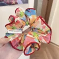 Colorful floral fabric scrunchie featuring elegant red trim and origin tag label - Red Apple Puppy