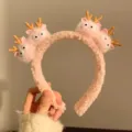 Close-up of a pink plush cartoon headband with cute antler characters. - Pink Deer