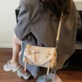 Retro beige pillow bag with belt and decorative zipper details worn by a model in a blazer. - Khaki