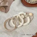 Set mit 5 cremefarbenen elastischen Haarbändern mit Herz- und Smiley-Anhängern - 5er-Pack / Milchkaffee
