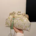 Elegant embroidered floral handbag featuring a vintage gold clasp and green tassel charm. - White