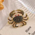 Detailed view of an ornate gold-tone crab brooch featuring black rhinestones and red eyes. - XZ158 Crab (XZ158) / Black