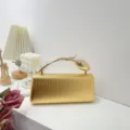Elegant gold metallic evening clutch bag with unique leaf-shaped handle on display - Gold