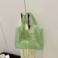 Κοντινό πλάνο πράσινης διαφανούς τσάντας PVC με τύπωμα TOTE BAG κρεμασμένη - ανοιχτό πράσινο