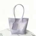 Detailed view of lavender TPU jelly tote bag with matching zippered pouch on marble - Light Purple