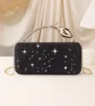Close-up of elegant black rhinestone evening clutch bag featuring a gold rose handle - Black