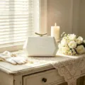 Elegant white crocodile texture evening clutch bag with gold curved clasp on lace table. - White